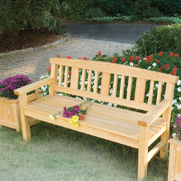 A cypress bench and matching planters in a garden setting with cobblestone path nearby.