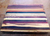 Multi-wood cutting board with routed juice groove along the edges on a workbench