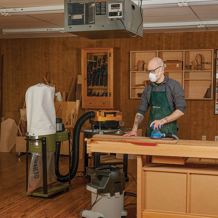 Woodworker in shop using some of the must have power tools for beginner woodworkers