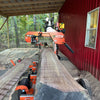 Portable sawmill cutting a large large tree into lumber.