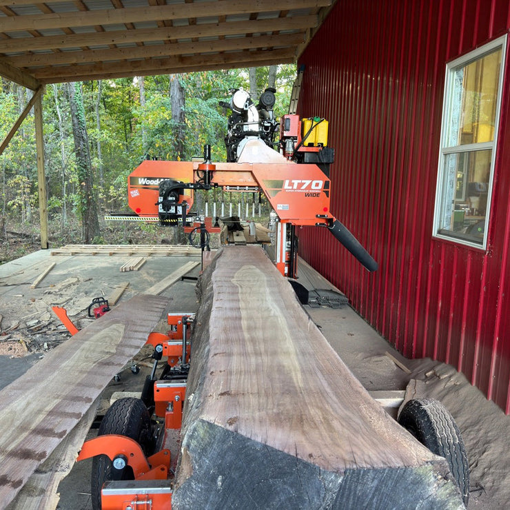 Portable sawmill cutting a large large tree into lumber.