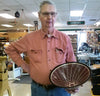 Older man in workshop holding segmented wood bowl with geometric pattern inside