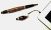 Two wood-bodied stylus pens next to a tablet, highlighting woodworking craftsmanship in electronic accessories.