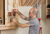 Woodworker organizing chisels and carving tools on a wall-mounted rack in workshop