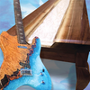 Electric guitar with blue resin body next to walnut table featuring white resin river inlay