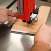 Woodworker using a bandsaw to make a cut to determine what type of bandsaw tune up work he needs to perform.