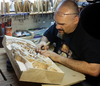 Woodworker carving detailed relief patterns into a large wood panel using a chisel