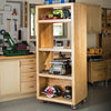 Mobile wooden tool storage tower with shelves holding power tools in a workshop.