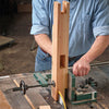 Woodworker using a cast-iron jig to cut mortise and tenon joints on a vertical wooden board