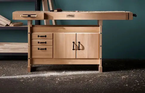 Wooden workbench with drawers and a cabinet against a teal wall.