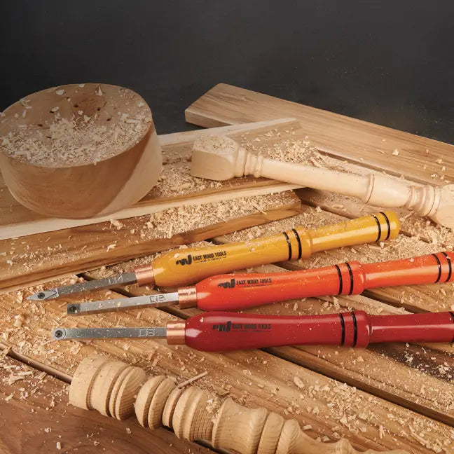 Set of wood carving tools on a wooden surface with wood shavings.