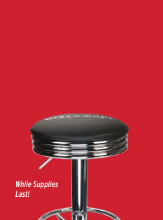 Bar stool with black cushioned seat and chrome base on a red background